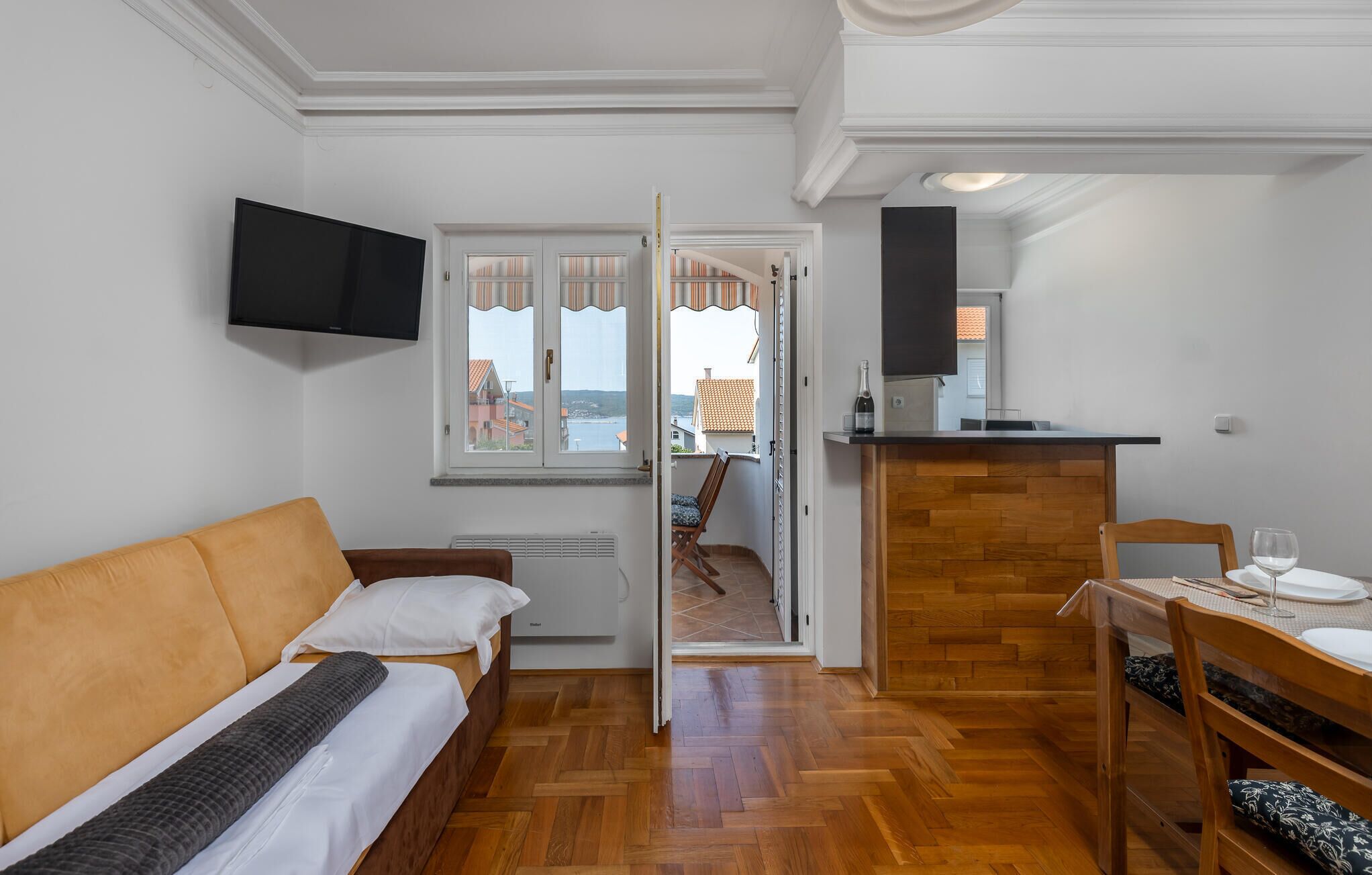 A compact room with a bed, a TV, a small kitchenette, and a balcony with a view.