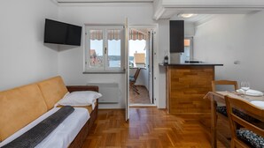 Une chambre compacte comprenant un lit, une télévision, une petite kitchenette et un balcon avec vue.