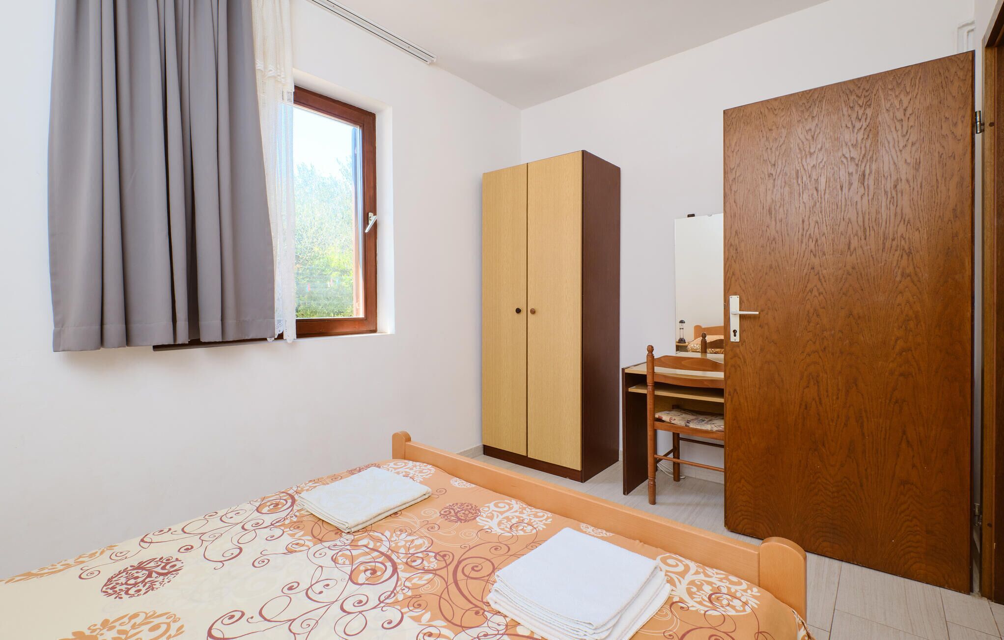 Una camera da letto con un letto, un armadio, una sedia e una porta.