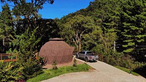 A vehicle parked near a large brick structure surrounded by dense greenery. - Estalagem da Montanha (Camanducaia)