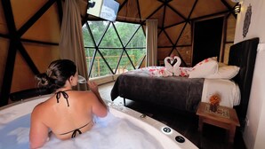 A room with a bed, a bathtub, and a window with a view of greenery. - Estalagem da Montanha (Camanducaia)