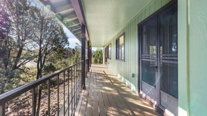 A wooden deck with a metal railing, a covered porch area, and large windows with mesh screens. - Prescott Family Getaway: Spacious 4-Bedroom Retreat with Game Room and Wildlife (Prescott)