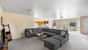 A living room with a sectional sofa, a coffee table, and a television. - Prescott Family Getaway: Spacious 4-Bedroom Retreat with Game Room and Wildlife (Prescott)