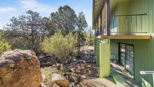 A green building with a balcony overlooking a rocky area and trees. - Prescott Family Getaway: Spacious 4-Bedroom Retreat with Game Room and Wildlife (Prescott)