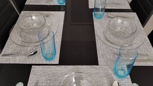 A dining table set with clear glassware, plates, and cutlery, surrounded by black chairs. - Nice first floor apartment (Barra Vieja)