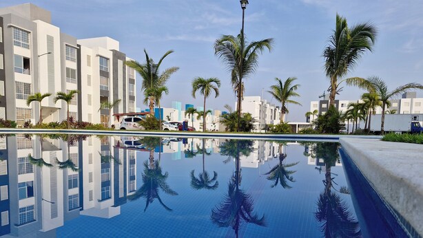 A modern hotel with a reflective pool, palm trees, and contemporary architecture. - Nice first floor apartment (Barra Vieja)