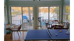 A room with a ping pong table, chairs, and a telescope.