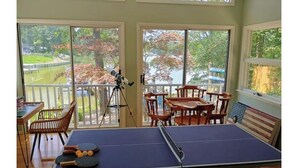 A ping pong table in a room with large windows, a telescope, and wooden furniture.