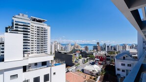 Un immeuble de grande hauteur doté de nombreux balcons et offrant une vue dégagée sur le paysage urbain et les montagnes au loin.