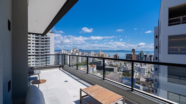 Un balcon offrant une vue sur le paysage urbain, avec des bâtiments et une étendue d’eau.
