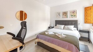 Een hotelkamer met een bed, een bureau, een stoel, een plafondventilator en kunst aan de muur.