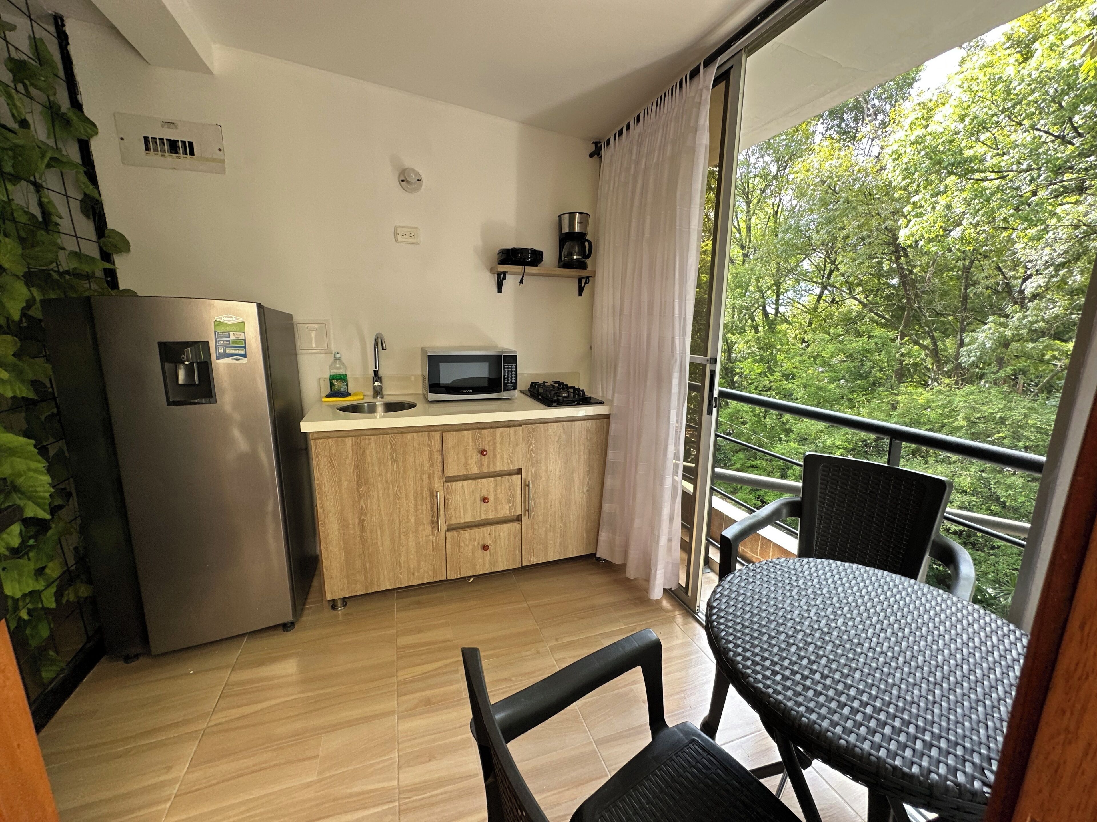 A compact kitchen with a refrigerator, microwave, and sink. A dining area with a table and chairs is visible.