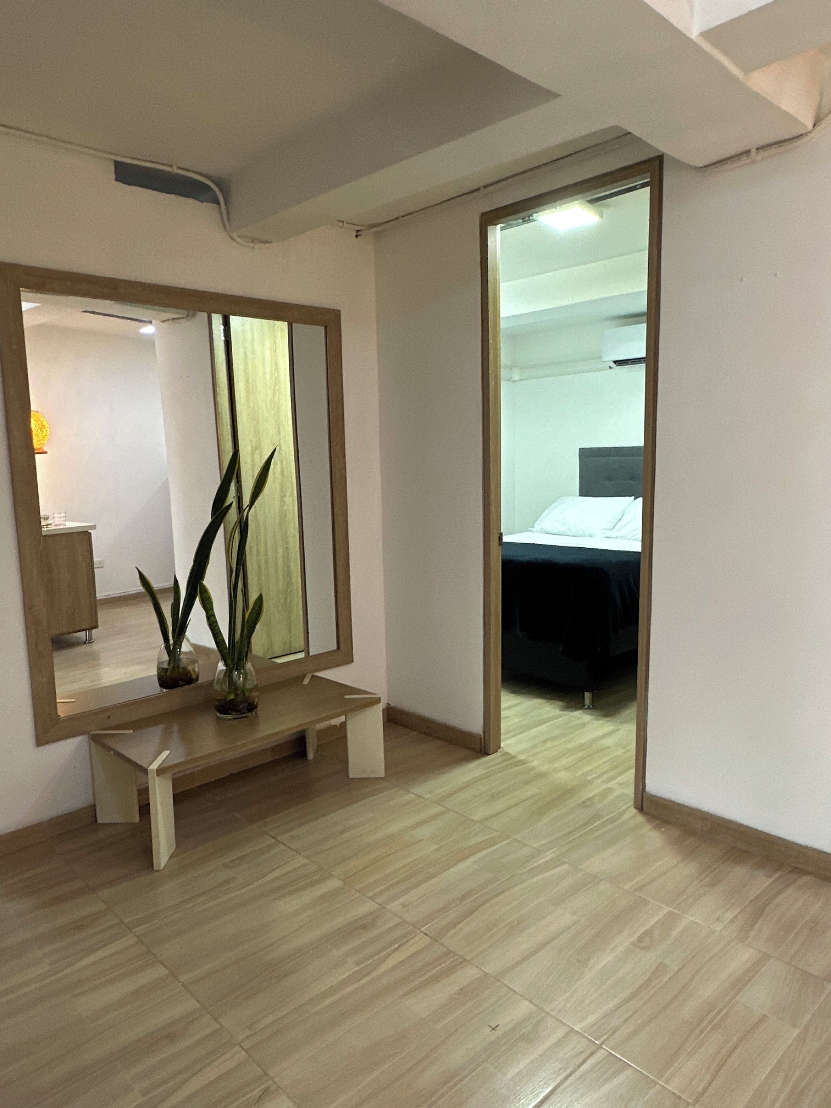Una camera d'albergo con una panca in legno, uno specchio grande e un letto.