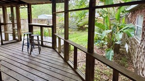 A covered outdoor area with wooden flooring, a table, and two stools. - Creatives Getaway in Gainesville Florida (Gainesville)