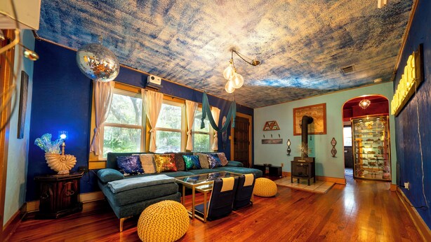 A room with a blue wall, wooden flooring, a sofa set, and a disco ball. - Creatives Getaway in Gainesville Florida (Gainesville)