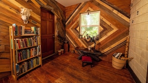 A cozy room with a wooden bookshelf, a window with a view of greenery, and a rustic decor including a skull and a woven basket. - Creatives Getaway in Gainesville Florida (Gainesville)