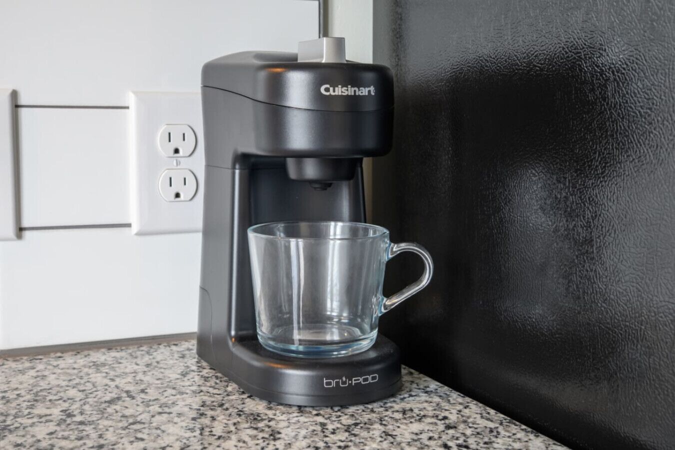 Une machine à café Cuisinart avec une tasse en verre, posée sur un comptoir en granit.