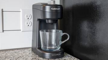 Une machine à café Cuisinart avec une tasse en verre, posée sur un comptoir en granit.