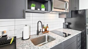 Une cuisine moderne avec des meubles de couleur sombre, un évier en acier inoxydable, un four à micro-ondes et un four encastré.