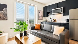 Ein modernes Wohnzimmer mit grauem Sofa, einem Holztisch und einer Topfpflanze.