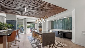 A modern kitchen with a central island, bar seating, and a geometric patterned rug.