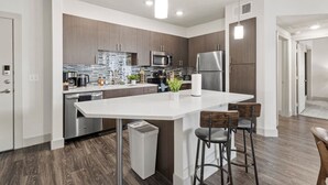 A modern kitchen with a central island, stainless steel appliances, and a wooden backsplash.