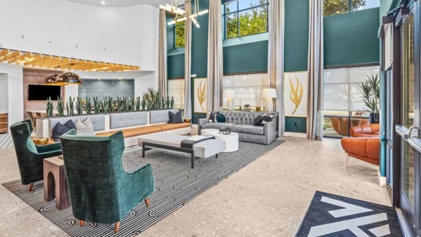 A spacious lobby with a modern sofa set, a coffee table, and a seating area with a patterned rug.