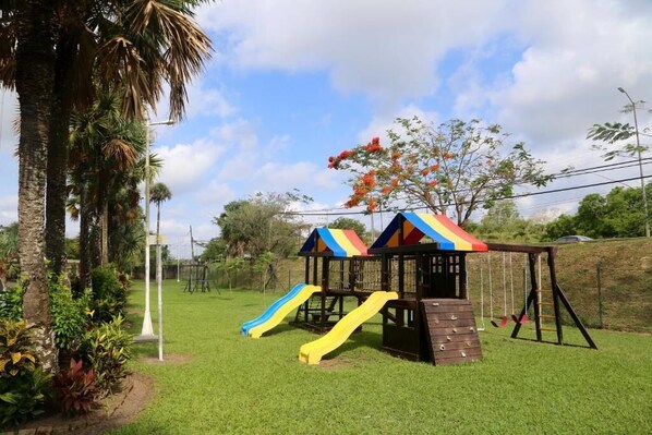 Un parque infantil con dos toboganes y columpios.