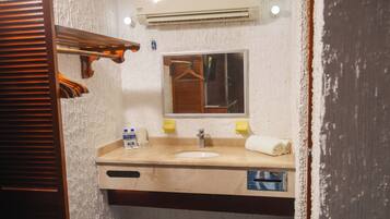 Un baño con lavamanos, espejo, toalla y un perchero.