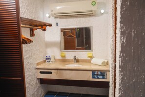 Un baño con lavamanos, espejo, toalla y un perchero.