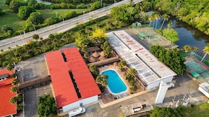 An aerial view of a property with a swimming pool, tennis courts, and a red-roofed building. - Hotel Plaza Palmas (Tuxpan)
