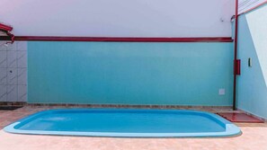A rectangular swimming pool with a light blue interior, surrounded by a tiled floor and walls painted in a light blue color. - Casa Amaral Pet-friendly com Piscina p 10 Pessoas (Iturama)