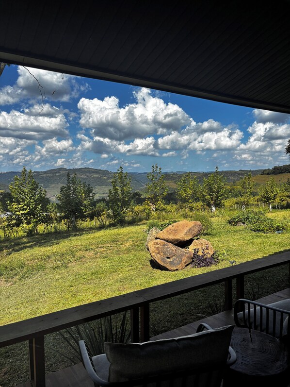 Vue depuis un espace extérieur abrité, doté d’une terrasse en bois, d’une table et de chaises.