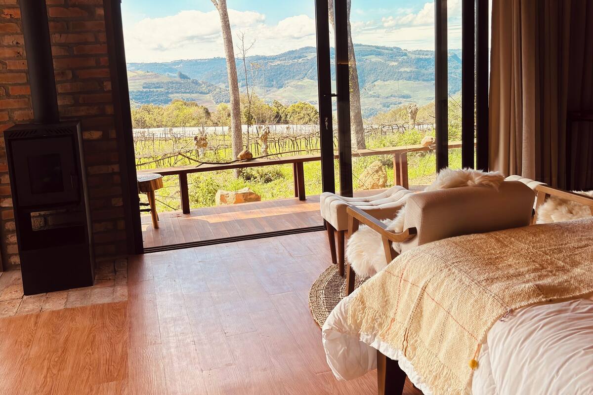 Un dormitorio con una cama grande, suelo de madera, chimenea y vistas al campo.
