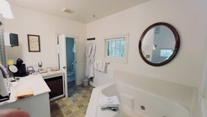 Ein Badezimmer mit einer Badewanne, einem Waschbecken, einem Spiegel und einem Fenster.