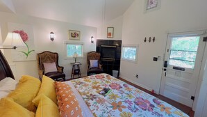 Ein Schlafzimmer mit einem Bett, zwei Stühlen, einem Fernseher und einer Tür.