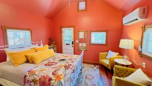 A bedroom with a bed, a chair, a nightstand, and a window.