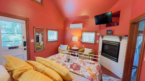 A room with a bed, a television, a fireplace, and a window with curtains.