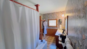 A bathroom with a shower curtain, a towel rack, a sink with a mirror, and a window.