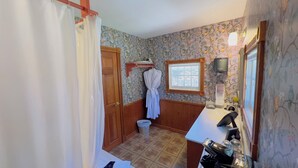 A bathroom with a wooden door, a window, a towel rack, a sink, and a mirror.