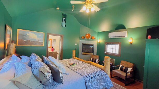 A bedroom with a bed, a chair, a TV, and a ceiling fan.