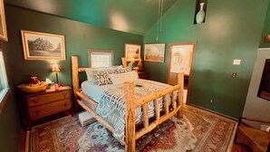 A bedroom with a wooden bed, a nightstand, a lamp, and a rug.