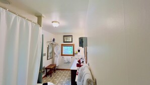 A bathroom with a shower curtain, a bench, a towel rack, a mirror, and a framed picture on the wall.
