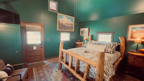 A bedroom with a bed, a chair, a nightstand, a lamp, and a window.