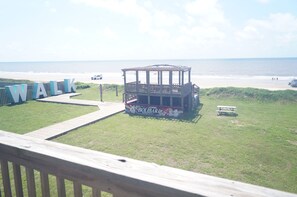 Vista sulla spiaggia con un pontile di legno, un gazebo e un cartello che dice 'WALK'.