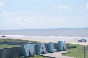 A beach with a wooden walkway and large letters spelling 'WALK' in the foreground. - Casa Dora - Pool, Games, & Beachfront Fun! 2nd fl. (Bolivar Peninsula)