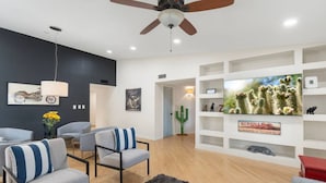 A modern living room with a ceiling fan, a mounted TV, and a cactus decoration. - Sun, Fun & a Tempe Tan Home (Tempe)