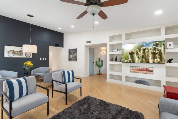 A modern living room with a ceiling fan, a mounted TV, and a cactus decoration. - Sun, Fun & a Tempe Tan Home (Tempe)