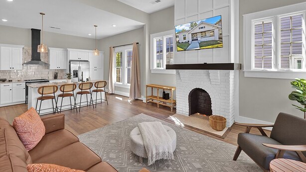A spacious living room with a fireplace, a kitchen with white cabinets, and a dining area with bar stools. - Avondale Charmer-Comfort & Style (Birmingham)