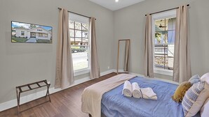 A bedroom with a bed, a ceiling fan, and a window with curtains. - Avondale Charmer-Comfort & Style (Birmingham)